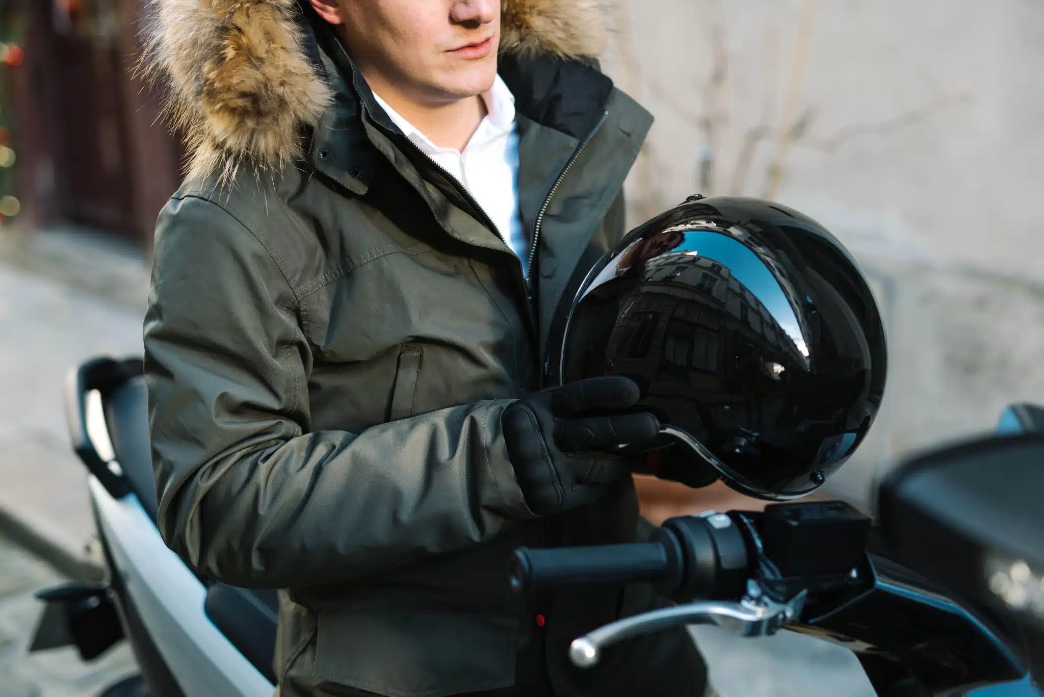 un homme avec son casque moto à la main